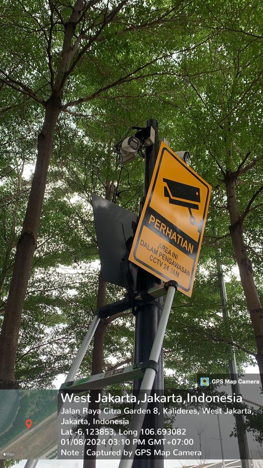 Kamera CCTV dan rambu peringatan area pengawasan pada tiang, difoto dari bawah