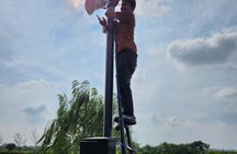 Teknisi memasang kamera CCTV dan speaker pada tiang di tepi danau kawasan
